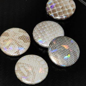 May include: Five round, iridescent, white and silver buttons with a textured, snake skin pattern.