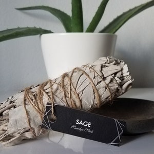 May include: A white sage smudge stick tied with twine, with a black tag that reads "SAGE Smudge Stick".