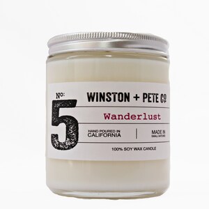 May include: A soy wax candle in a clear glass jar with a silver lid. The label reads "WINSTON + PETE CO" and "Wanderlust". The number "5" is prominently displayed. The candle is hand-poured in California.