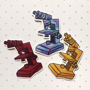 May include: Three illustrated microscope stickers. One is blue with a galaxy pattern, one is yellow, and one is red.