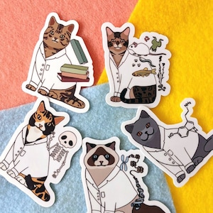 Puede incluir: Cinco pegatinas de gatos con diferentes temas científicos. Cada gato lleva una bata de laboratorio blanca y tiene un elemento científico diferente en su pegatina. Las pegatinas de gatos están sobre un fondo azul y naranja.
