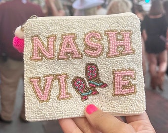 Op de afbeelding: Witte kralen tas met roze en gouden letters die "NASHVILLE" lezen met een paar roze en blauwe kralen cowboylaarzen in het midden.