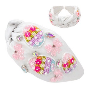 May include: White headband with a knotted design and embellished with colorful beaded eggs and butterflies.