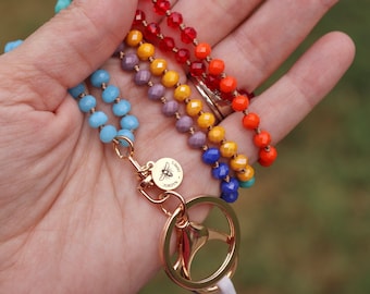 Puede incluir: Un cordón con cuentas multicolores, con cuentas azules, moradas, amarillas, naranjas y rojas. El cordón tiene un cierre dorado y un dije con un diseño de abeja. Las cuentas son facetadas y ensartadas en un cordón.