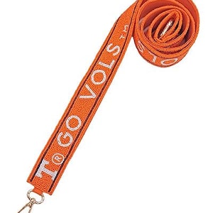 Puede incluir: Correa de cuentas naranja con el texto "I GO VOLS TM" en blanco.