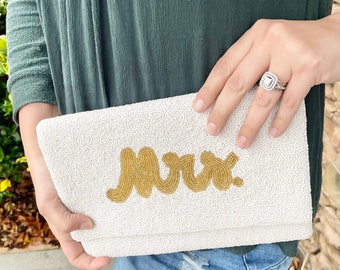 May include: A white beaded clutch with the word "Mrs." spelled out in gold beads.