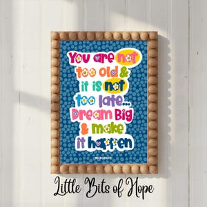 Może przedstawiać: Oprawiony wydruk z niebieskim tłem i białymi kropkami. Wydruk zawiera kolorowy tekst o treści "You are not too old & it is not too late... Dream Big & make it happen." Rama jest drewniana.