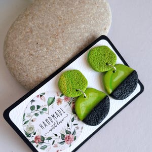 Può includere: Orecchini verde lime e neri con finitura strutturata. Gli orecchini sono esposti su un cartoncino bianco con bordo nero e un motivo floreale. La carta ha anche il testo "HANDMADE with love".