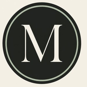 Op de afbeelding: Een rond grafisch embleem met een effen zwart midden en een grote, witte, schreef-stijl hoofdletter M in het centrum. De zwarte cirkel is omsloten door een dunne, licht saliegroene rand, wat zorgt voor een strak en gebalanceerd ontwerp.