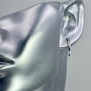 May include: A silver mannequin head with a silver hoop earring in the right ear.