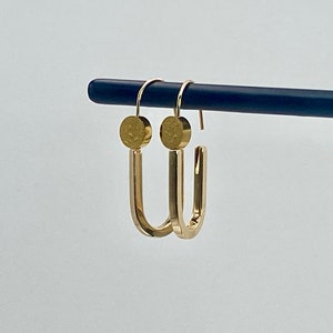 May include: A pair of gold hoop earrings with a textured circular design at the top of each hoop.