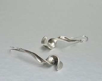 May include: A pair of silver earrings with a twisted, hammered design. The earrings are long and dangle.