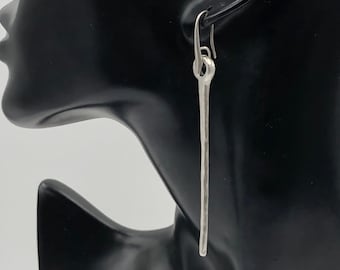 May include: A silver dangle earring with a hammered finish and a simple hook closure.
