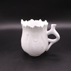 May include: White ceramic shaving mug with a tulip-shaped design and a handle. The mug has a smooth, glossy finish.