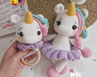 Puede incluir: Conjunto de muñeca y sonajero de unicornio de ganchillo. El unicornio blanco tiene un cuerno amarillo, mejillas rosas y un tutú lavanda. El sonajero presenta un anillo de madera y una cabeza de unicornio a juego. El texto "Iris Unicornio" es visible.