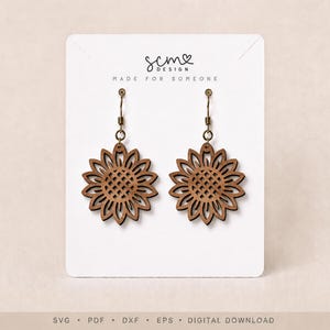 May include: A pair of brown wooden sunflower-shaped earrings with dark metal hooks attached to a white display card. The card features the text scm DESIGN MADE FOR SOMEONE at the top and SVG PDF DXF EPS DIGITAL DOWNLOAD at the bottom.