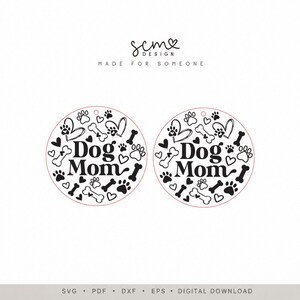 K&ouml;nnte beinhalten: Zwei identische kreisf&ouml;rmige Designs mit dem schwarzen Text Dog Mom in der Mitte, umgeben von einem Muster aus schwarzen Pfotenabdr&uuml;cken, Herzen und Knochen auf wei&szlig;em Grund. Oben steht der Text scm DESIGN MADE FOR SOMEONE.