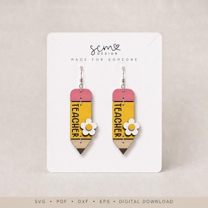 May include: A pair of dangle earrings shaped like yellow pencils with pink erasers, a brown tip, and a white flower accent. The word TEACHER is printed vertically in black on each pencil. The earrings are displayed on a white card with the text scm design MADE FOR SOMEONE.