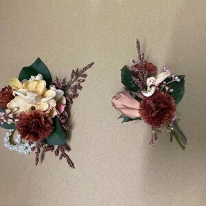May include: Two floral arrangements with a mix of pink, white, and burgundy flowers. One arrangement features a pearl necklace and the other has a single pink rose.