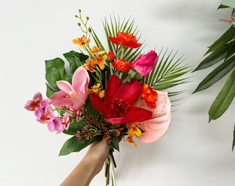 Könnte beinhalten: Ein tropischer Blumenstrauß mit rosa Orchideen, rotem Anthurium, orangefarbenen und gelben Blüten und grünen Blättern.