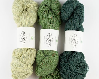 May include: Three skeins of yarn in green and light green colors. The yarn is labeled "Loch Lomond Lace" and is made of 100% Organic Wool.
