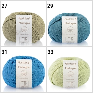 May include: Four skeins of yarn in different colors: green, blue, light blue, and light green. Each skein has a label that reads "Ros&aacute;rios 4. Madragoa" and includes information about the yarn, such as "Fibras Naturais Natural Fibers" and "Ecofriendly Collection".