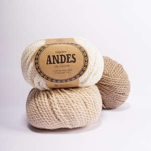 May include: Two balls of yarn, one white and one beige, with a brown label that reads "DROPS ANDES UNI COLOUR A soft and chunky blend of alpaca and wool"