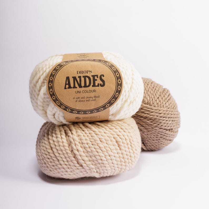 May include: Two balls of yarn, one white and one beige, with a brown label that reads "DROPS ANDES UNI COLOUR A soft and chunky blend of alpaca and wool"