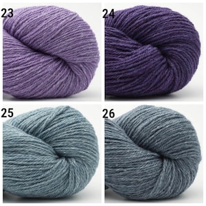 May include: Four skeins of yarn in different colors: a light purple, a dark purple, a light blue, and a dark blue. The yarn is arranged in a grid pattern.