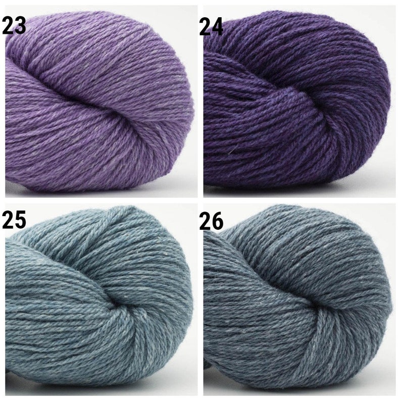May include: Four skeins of yarn in different colors: a light purple, a dark purple, a light blue, and a dark blue. The yarn is arranged in a grid pattern.