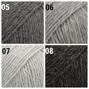 May include: Four skeins of yarn in different shades of gray. The skeins are labeled 05, 06, 07, and 08.