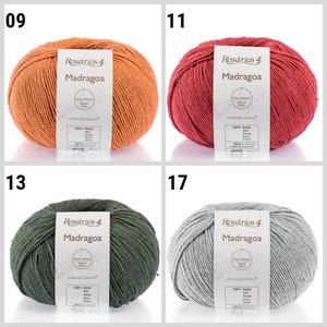 May include: Four skeins of yarn in different colors: orange, red, green, and gray. Each skein has a label that reads "Ros&aacute;rios 4. Madragoa" and includes information about the yarn's composition and origin.