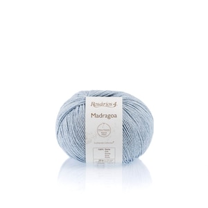 May include: A ball of light blue yarn labeled "Ros&aacute;rios 4 Madragoa" with the text "Fibras Naturais Natural Fibers Ecofriendly Collection 100% Seda Silk Seide Soie Seta Seta"