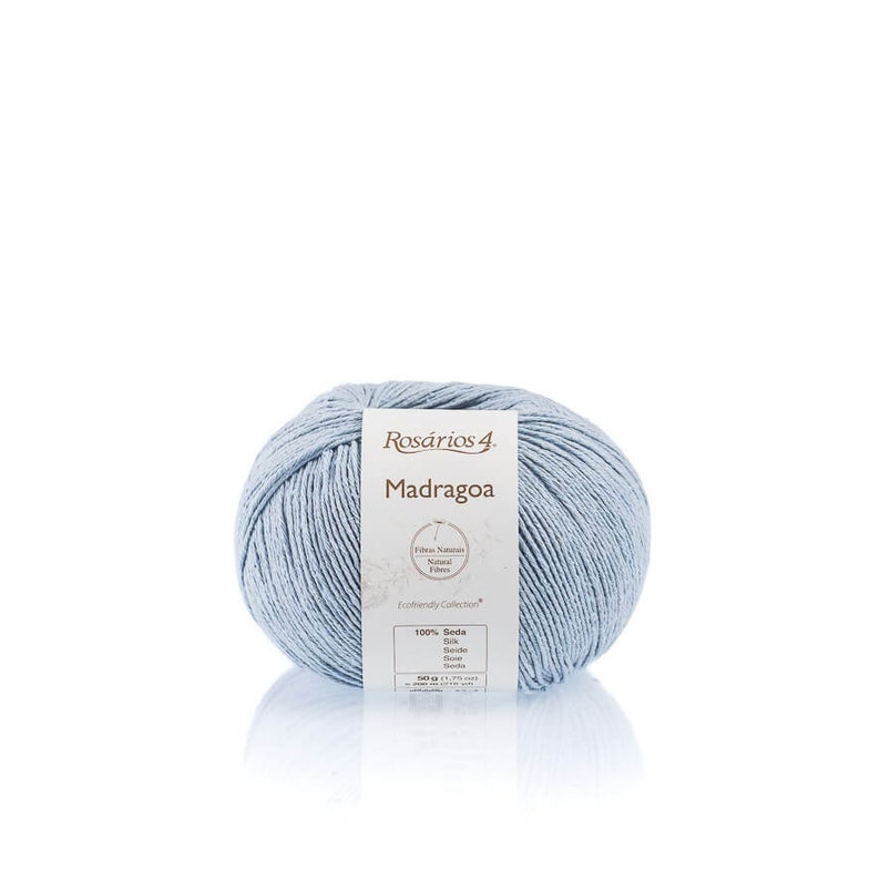 May include: A ball of light blue yarn labeled "Ros&aacute;rios 4 Madragoa" with the text "Fibras Naturais Natural Fibers Ecofriendly Collection 100% Seda Silk Seide Soie Seta Seta"