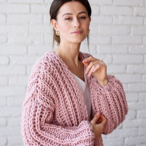 Pu&ograve; includere: Un cardigan di maglia rosa con una trama a maglia grossa e maniche lunghe. Il cardigan &egrave; aperto sul davanti e ha una vestibilit&agrave; rilassata.
