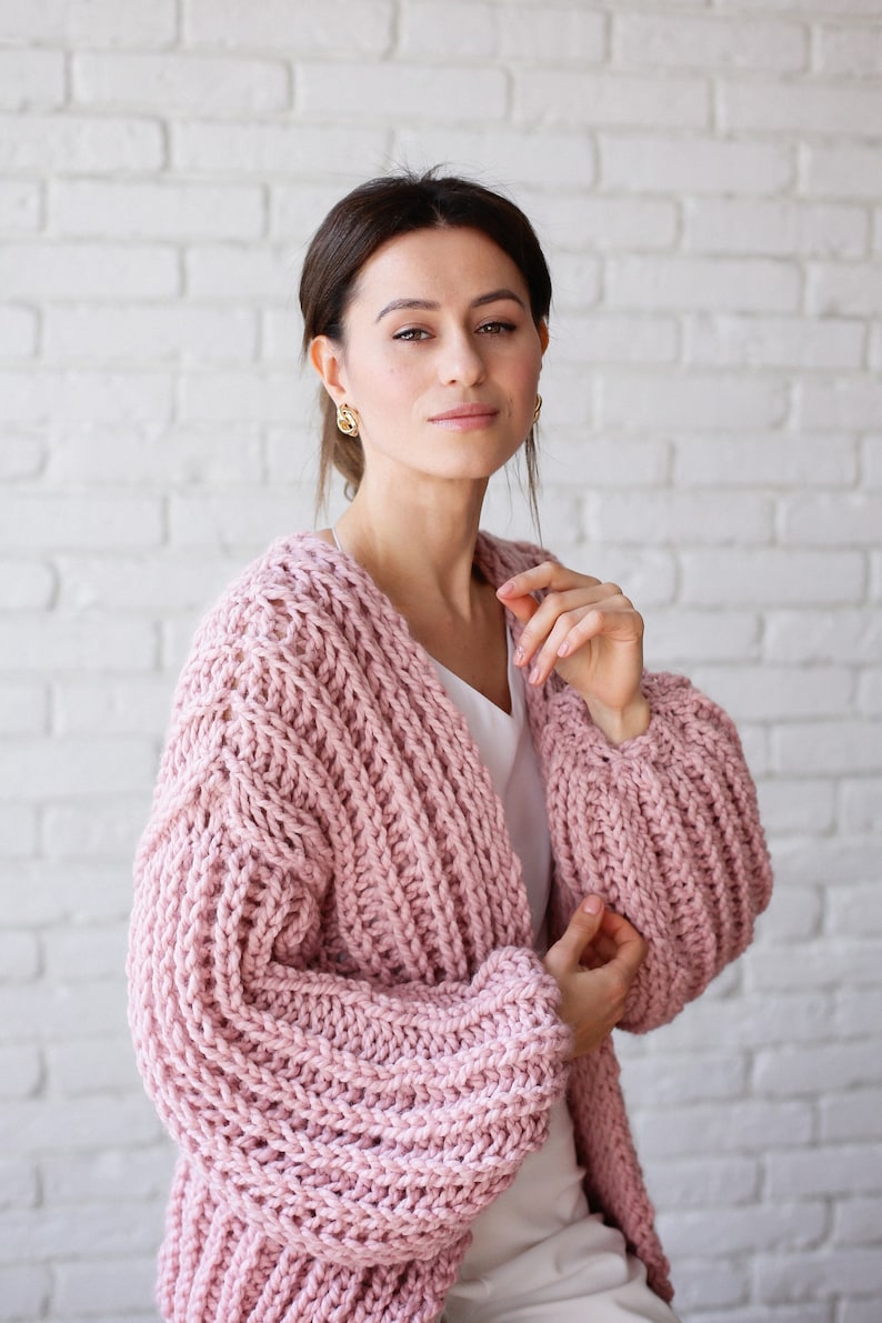 Pu&ograve; includere: Un cardigan di maglia rosa con una trama a maglia grossa e maniche lunghe. Il cardigan &egrave; aperto sul davanti e ha una vestibilit&agrave; rilassata.