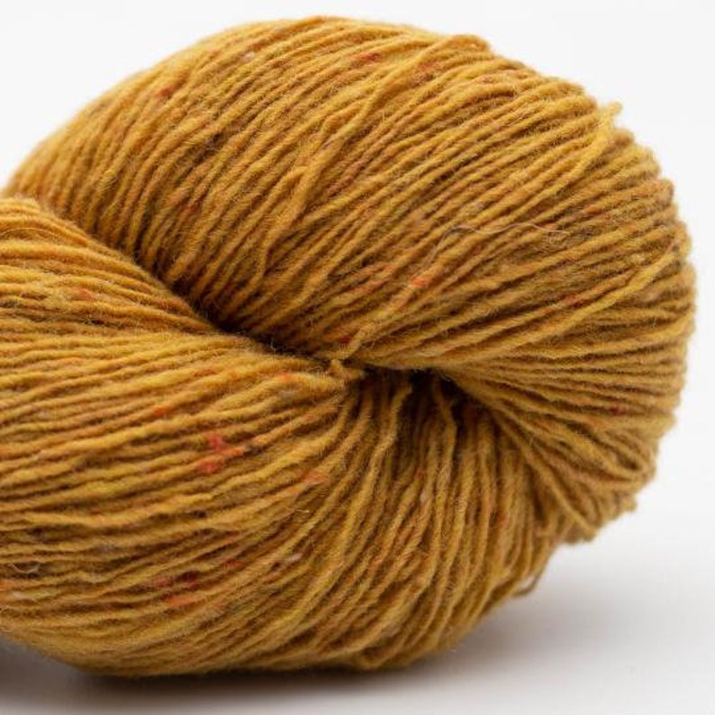 May include: A skein of yarn in a warm, golden yellow color with subtle flecks of orange throughout. The yarn is soft and fluffy, and it is perfect for knitting or crocheting.