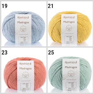 May include: Four skeins of yarn in different colors: light blue, yellow, peach, and light green. Each skein has a label that reads "Ros&aacute;rios 4 Madragoa" and includes information about the yarn, such as the fiber content and weight.