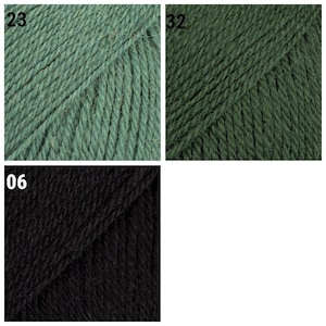 K&ouml;nnte beinhalten: Nahaufnahme von drei Garnkn&auml;ueln in verschiedenen Farben. Oben links ist ein ged&auml;mpftes Gr&uuml;n mit der Nummer 23. Oben rechts ist ein dunkleres Gr&uuml;n mit der Nummer 32. Unten ist ein schwarzes Kn&auml;uel mit der Nummer 06.