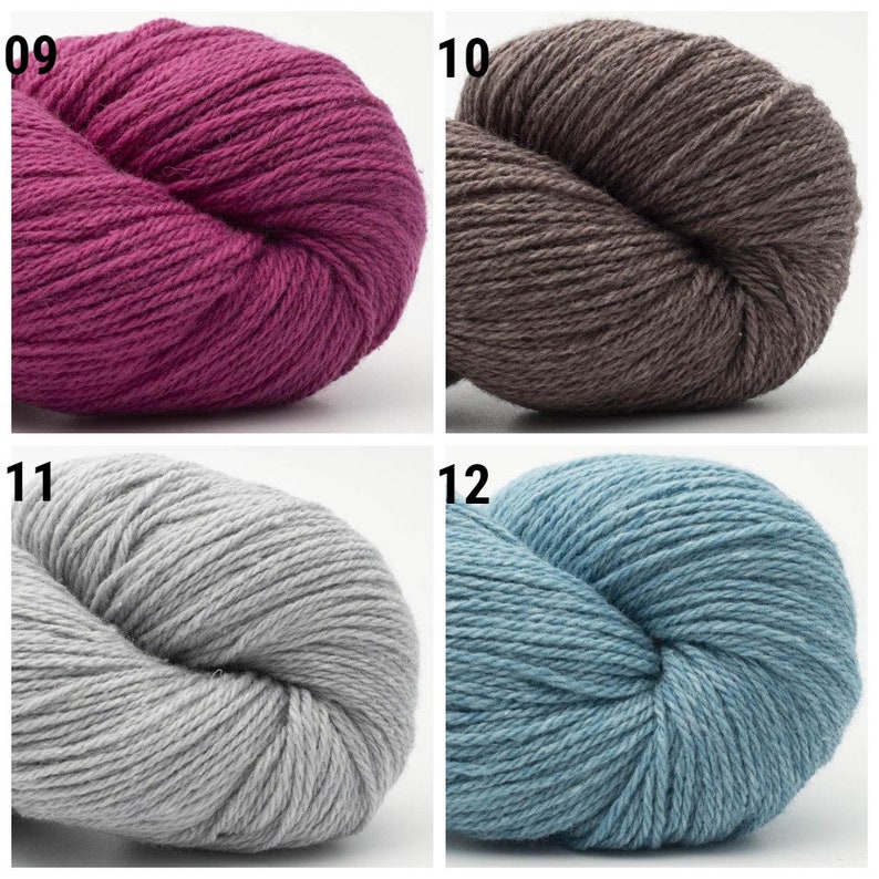 May include: Four skeins of yarn in different colors: a deep pink, a brown, a light gray, and a light blue. The yarn is arranged in a circle, with the ends of the skeins meeting in the center.