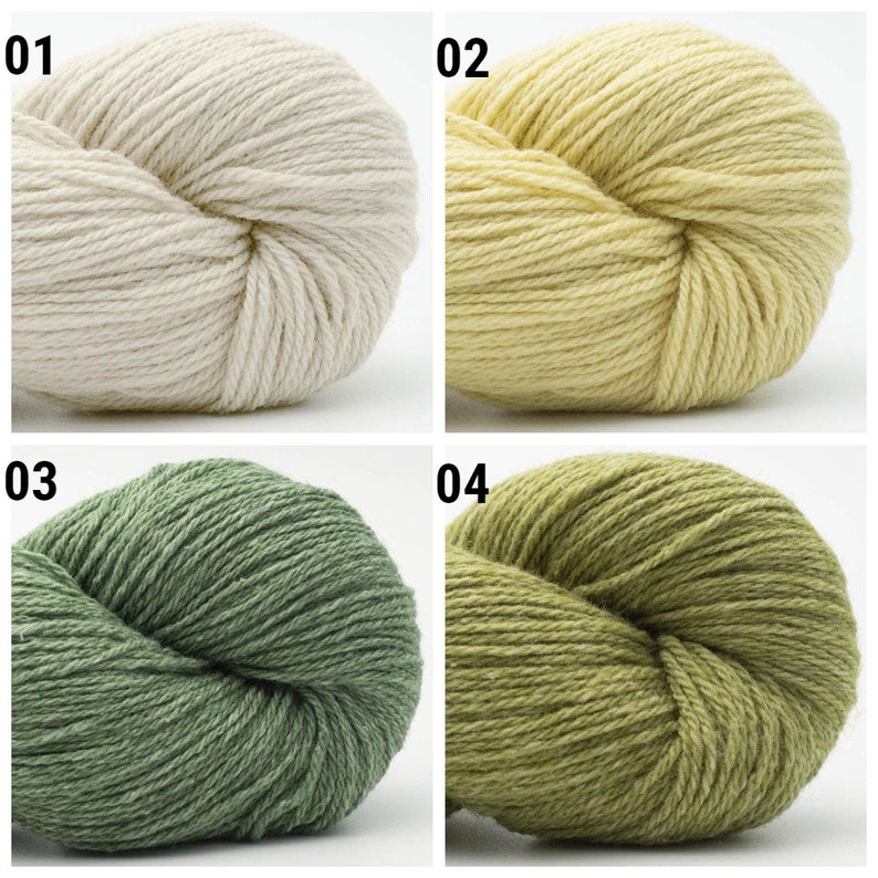 May include: Four skeins of yarn in different colors: white, yellow, green, and a darker green. The yarn is wound into balls.