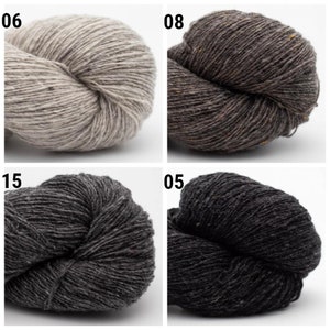 May include: Four skeins of yarn in different colors: light beige, dark brown, dark gray, and black. The yarn is textured and has a subtle fleck.