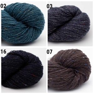 May include: Four skeins of yarn in different colors: teal, dark blue, navy blue, and brown. Each skein has a speckled pattern.