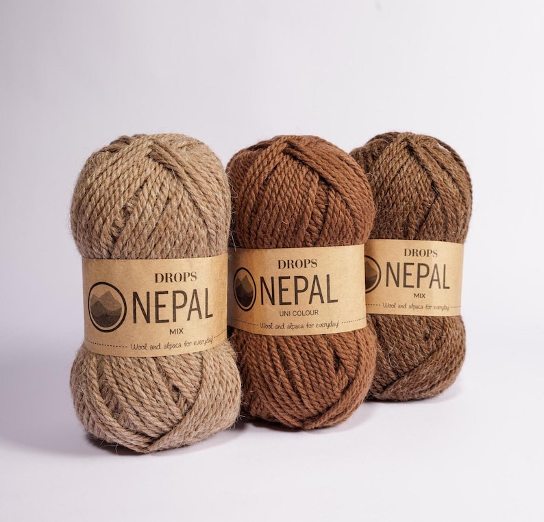 May include: Three skeins of DROPS Nepal yarn in different colors: brown, tan, and a mix of brown and tan. The yarn is made of wool and alpaca and is labeled "Wool and alpaca for everyday."