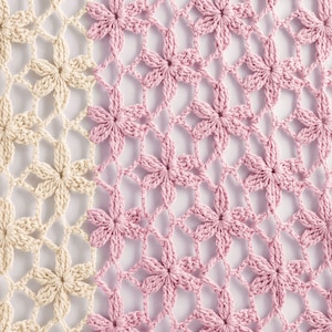 May include: A close-up of a crocheted fabric with a pattern of flowers. The fabric is half beige and half pink.