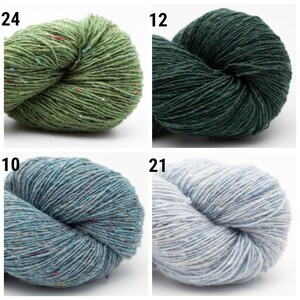 May include: Four skeins of yarn in different colors: green with red flecks, dark green, blue with white flecks, and light blue with white flecks.