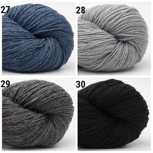 May include: Four skeins of yarn in different colors: blue, gray, dark gray, and black. The yarn is arranged in a grid pattern with the numbers 27, 28, 29, and 30 printed above each skein.
