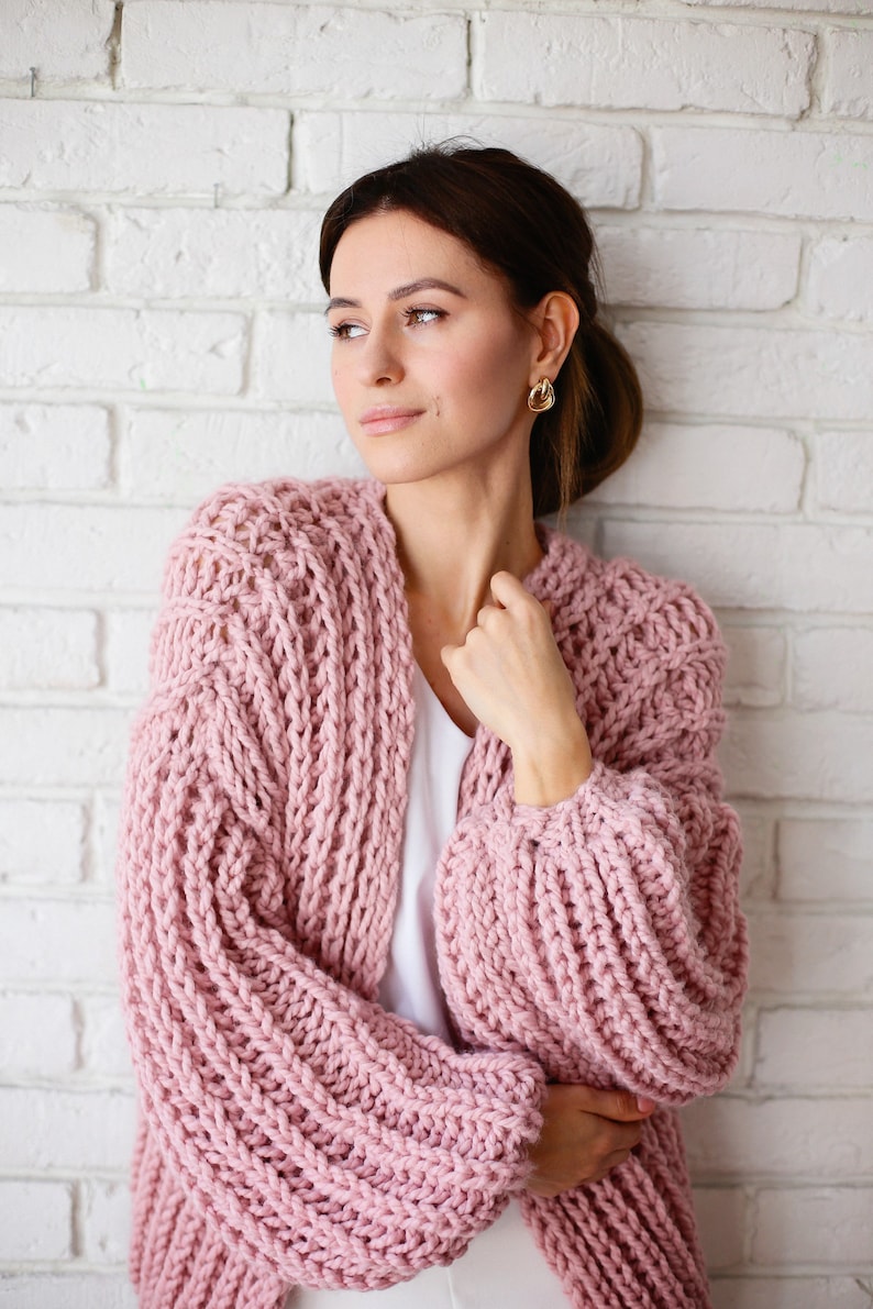 Pu&ograve; includere: Un cardigan rosa lavorato a maglia con una vestibilit&agrave; ampia e maniche lunghe. Il cardigan &egrave; realizzato con un filato spesso e ha uno stile rilassato e casual.