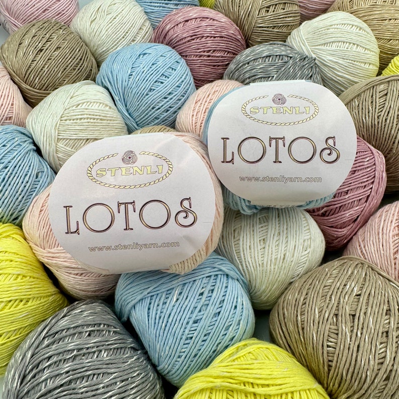 May include: A variety of yarn balls in different colors, including light blue, pink, beige, and yellow. The yarn balls have a label that says "Stenli Lotos" and a website address.