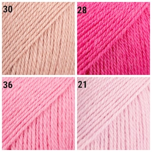 K&ouml;nnte beinhalten: Nahaufnahme von vier Garnkn&auml;ueln in verschiedenen Rosa- und Beiget&ouml;nen. Das Garn ist eng gewickelt und zeigt die Textur der Fasern. Die Farben umfassen ein helles Beige, ein leuchtendes Rosa, ein mittleres Rosa und ein blasses Rosa. Jedes Kn&auml;uel hat ein nummeriertes Etikett.